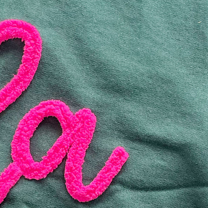 hot pink yarn on dark green embroidered sweatshirt