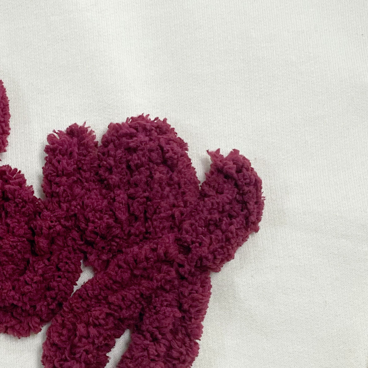 maroon yarn on off white embroidered sweatshirt