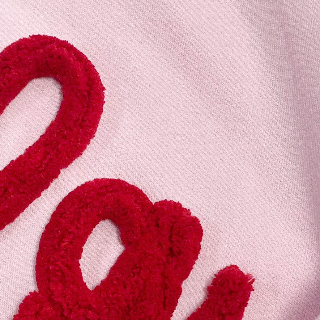 red yarn on light pink embroidered sweatshirt